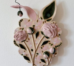 Keraaminen seinäkoriste kukilla ja lehdillä