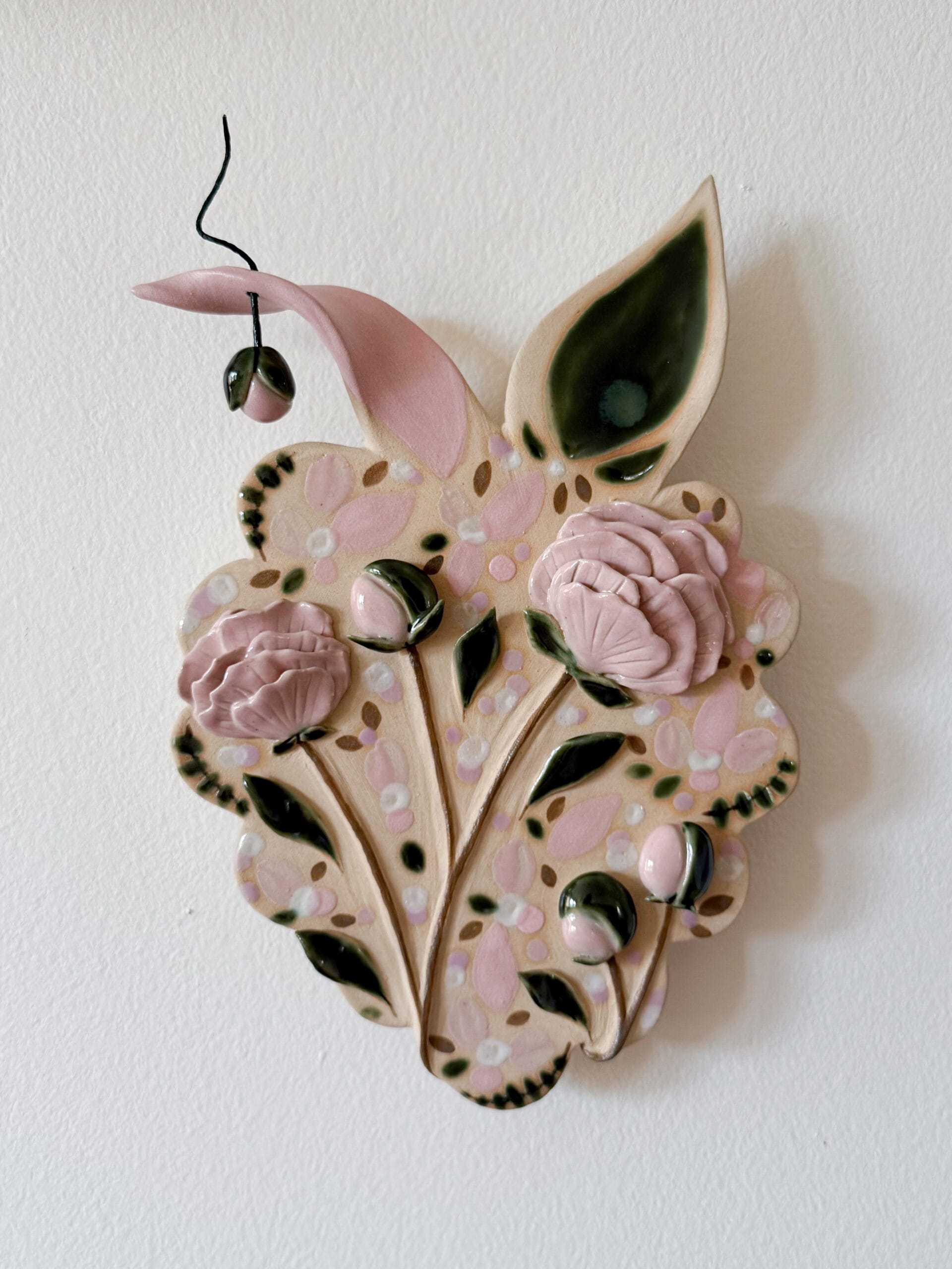 Keraaminen seinäkoriste kukilla ja lehdillä