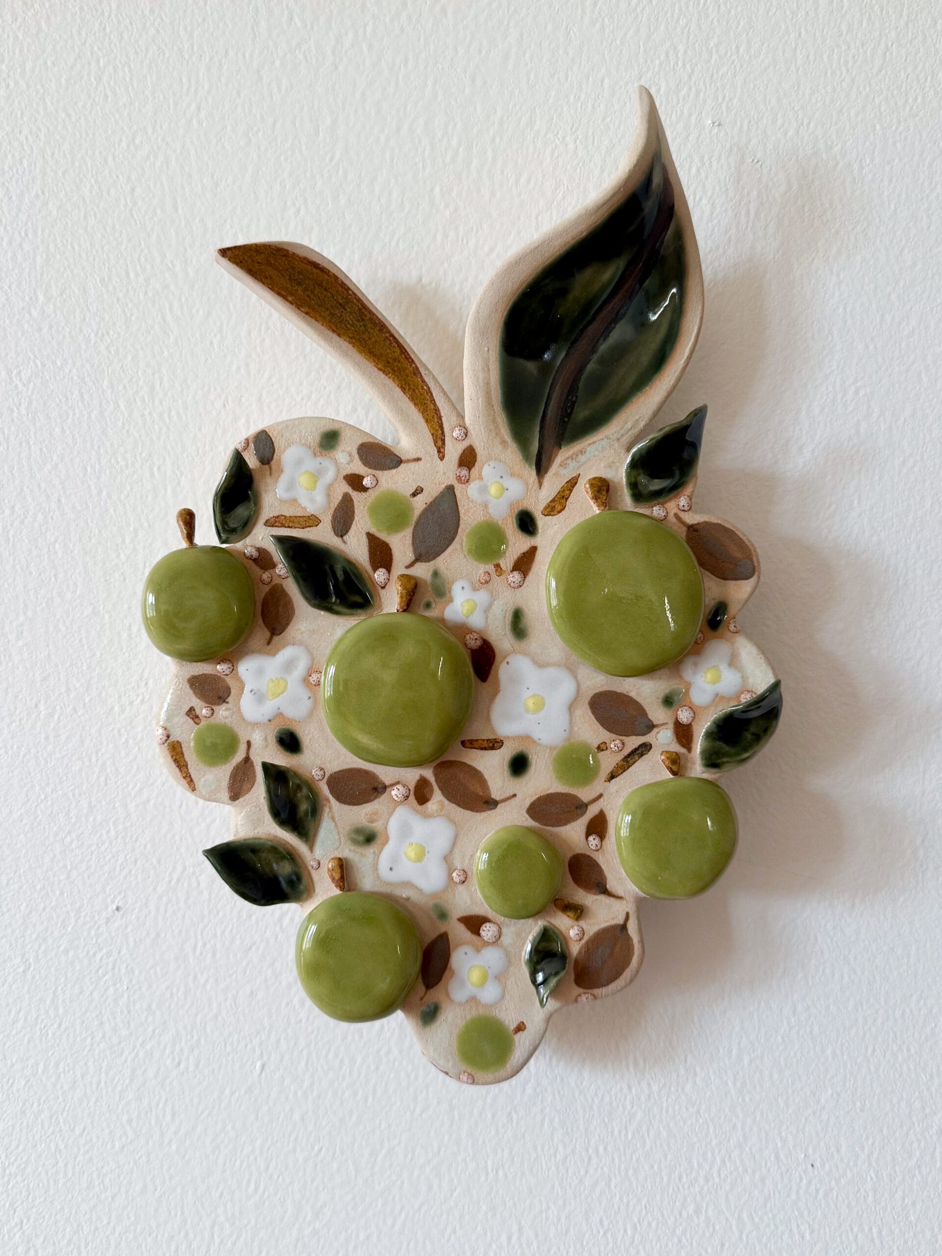 Keramiikkalehti vihreillä ja valkoisilla kiinnostavilla yksityiskohdilla.