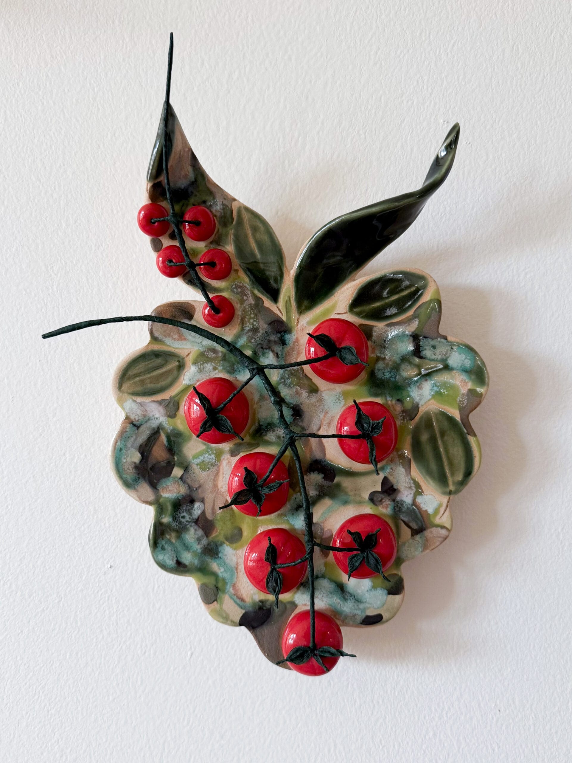 Keraaminen seinäkoriste ja punaisia marjoja