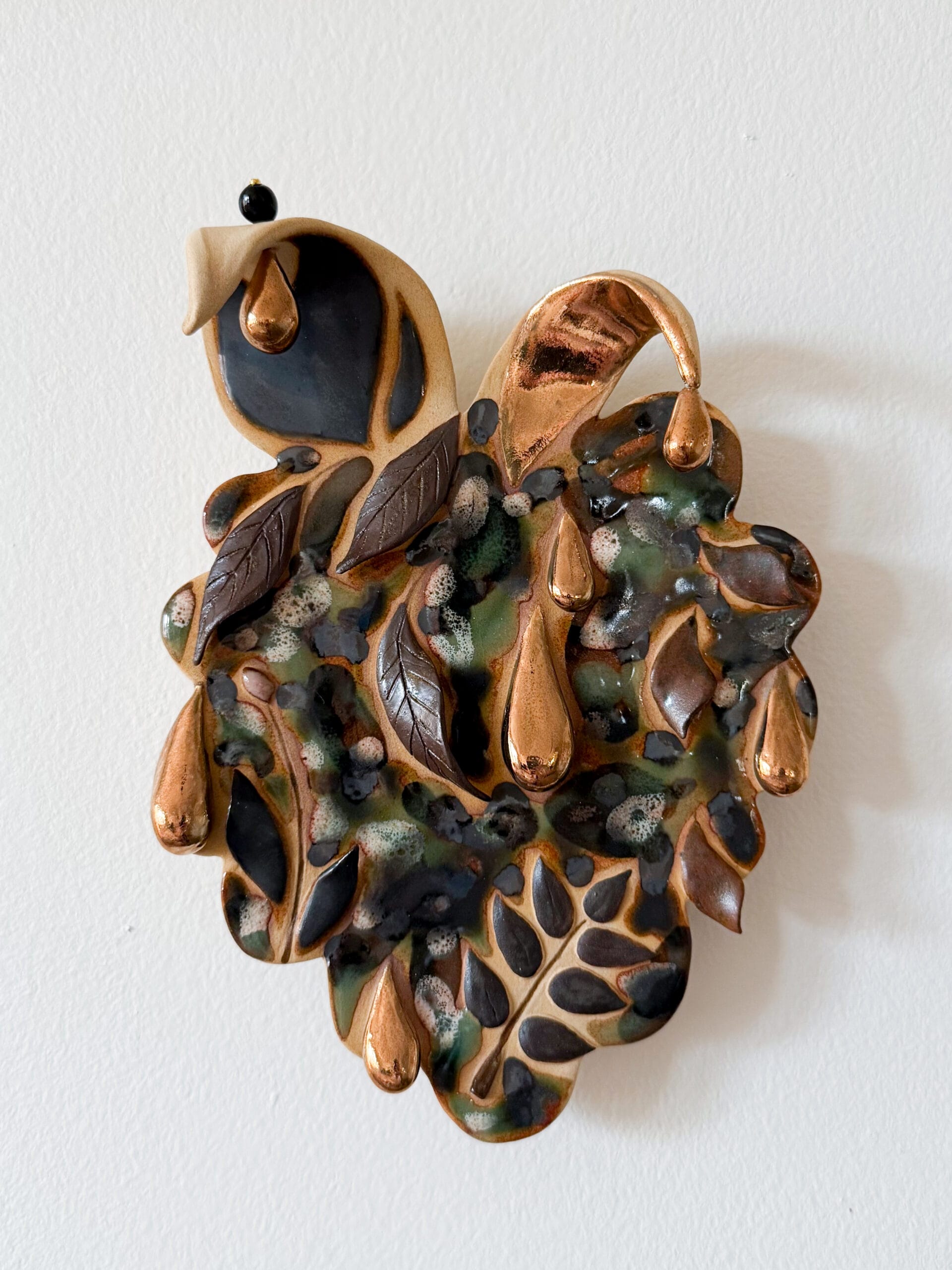 Keraaminen lehtiriipus, metalliset pisarad koristavat.