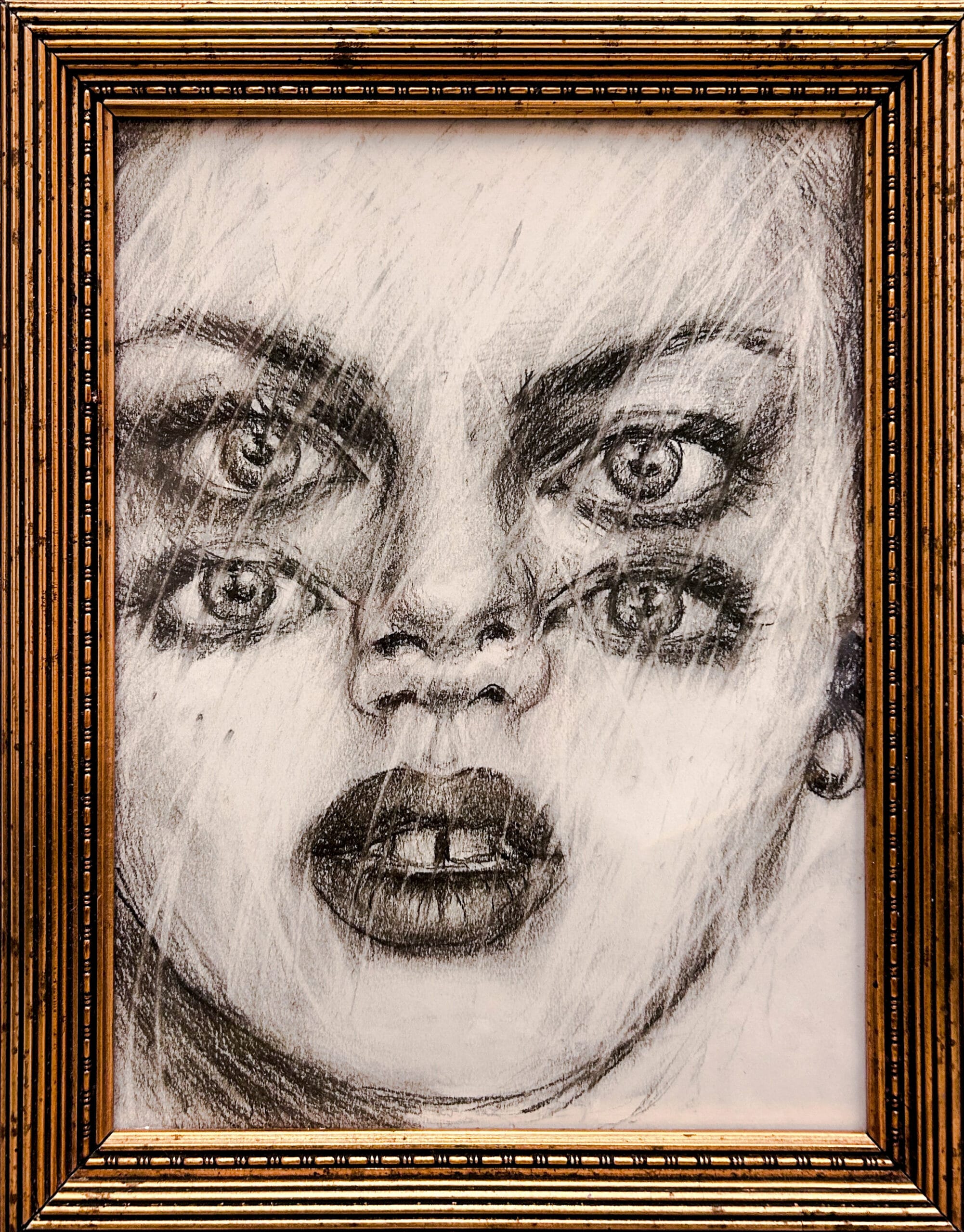 Kaksikasvoinen ja monisilmäinen piirros kullatussa kehyksessä.