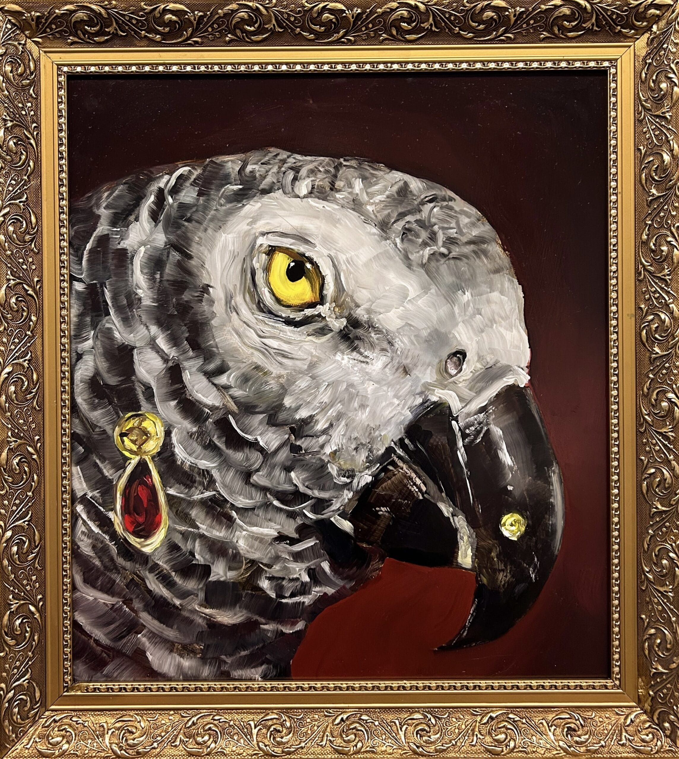 Papukaijan taulu kultakehyksissä, korvakoru vasemmalla.