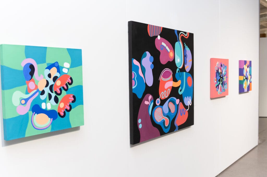 Abstrakteja värikkäitä maalauksia ripustettuna galleriassa