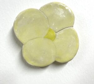 Vaaleankeltainen keramiikkakukka valkoisella taustalla