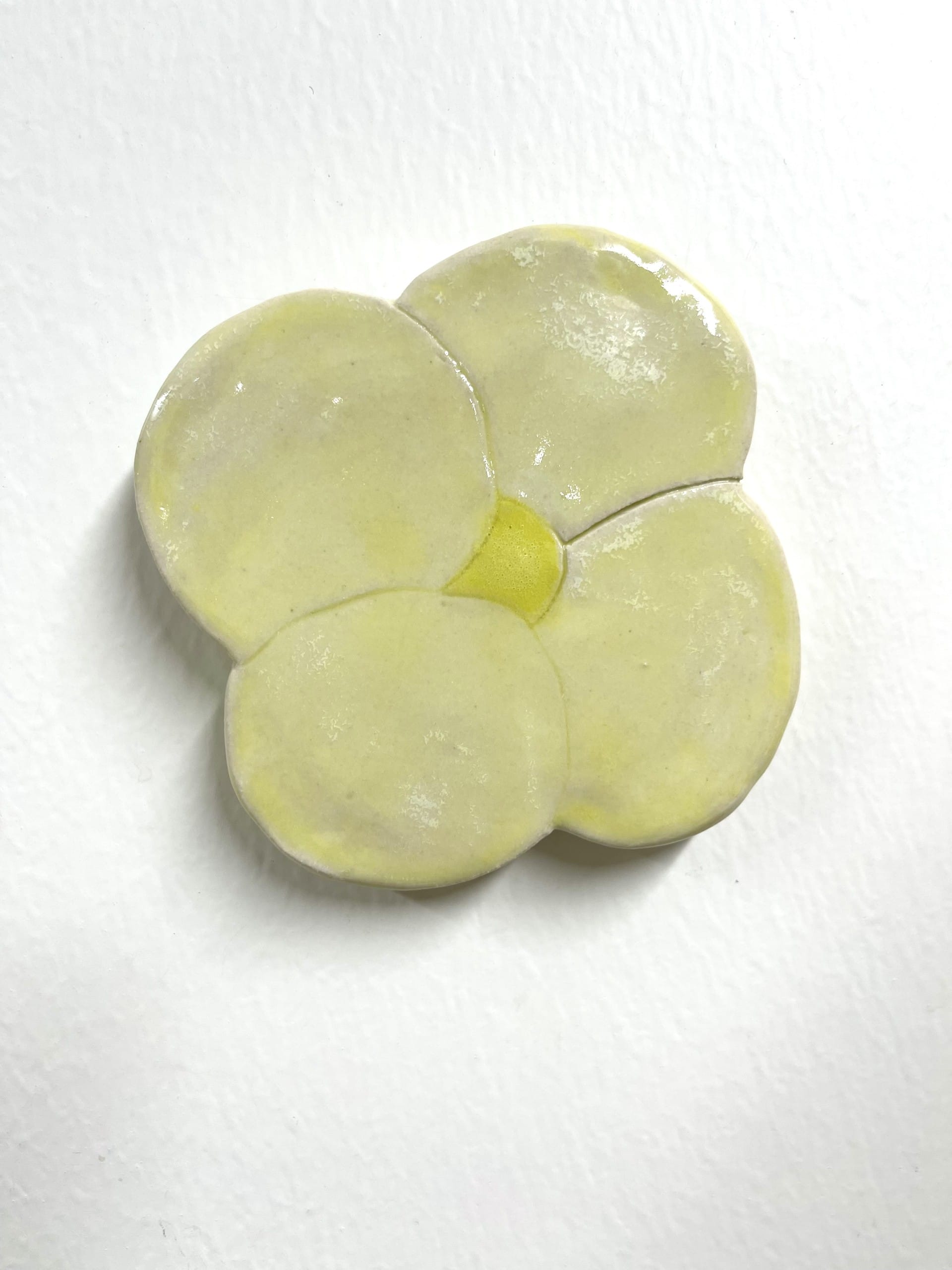 Vaaleankeltainen keramiikkakukka valkoisella taustalla