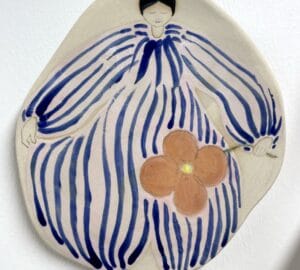 Keraaminen koriste naishahmolla ja kukalla