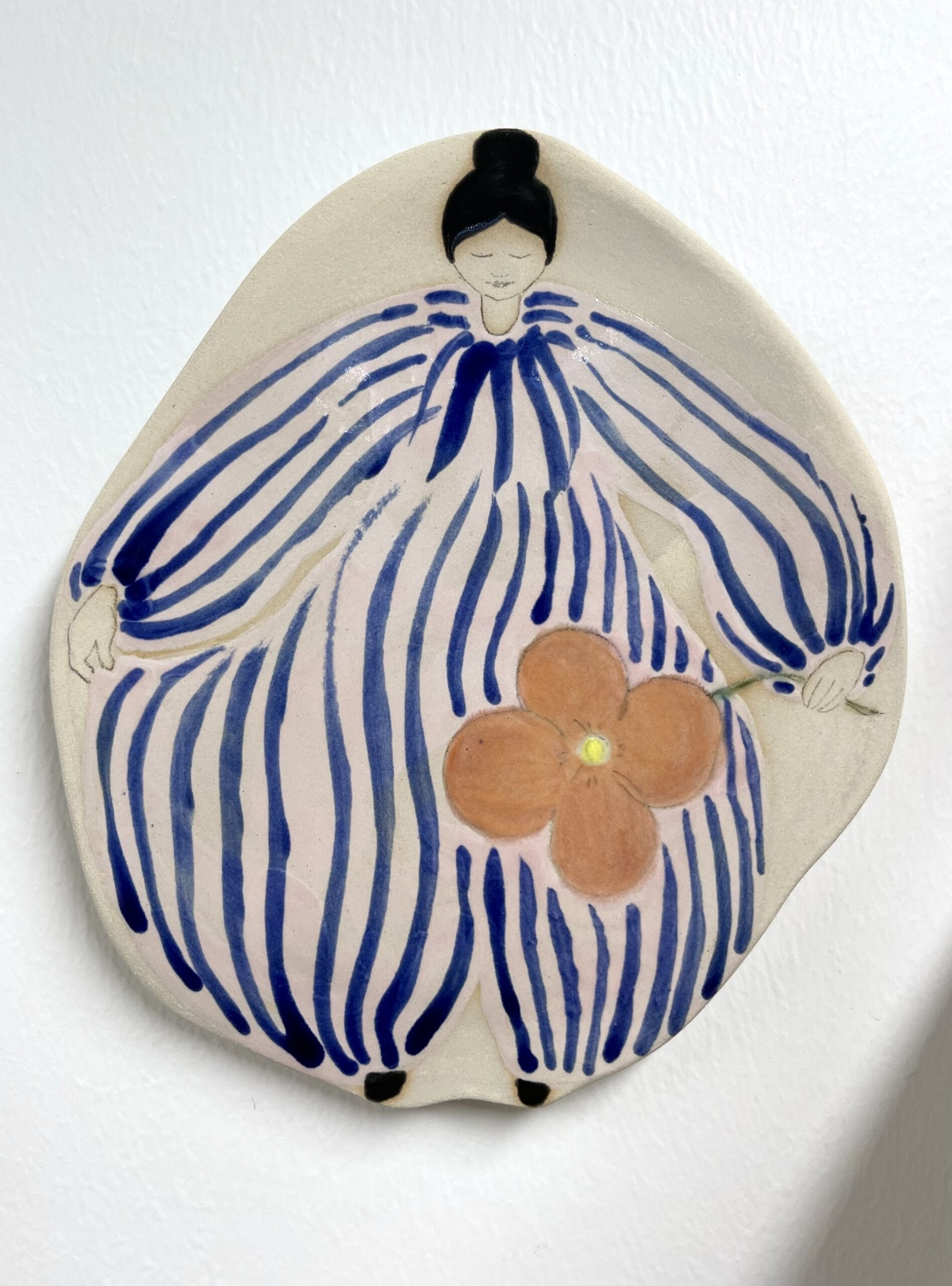 Keraaminen koriste naishahmolla ja kukalla