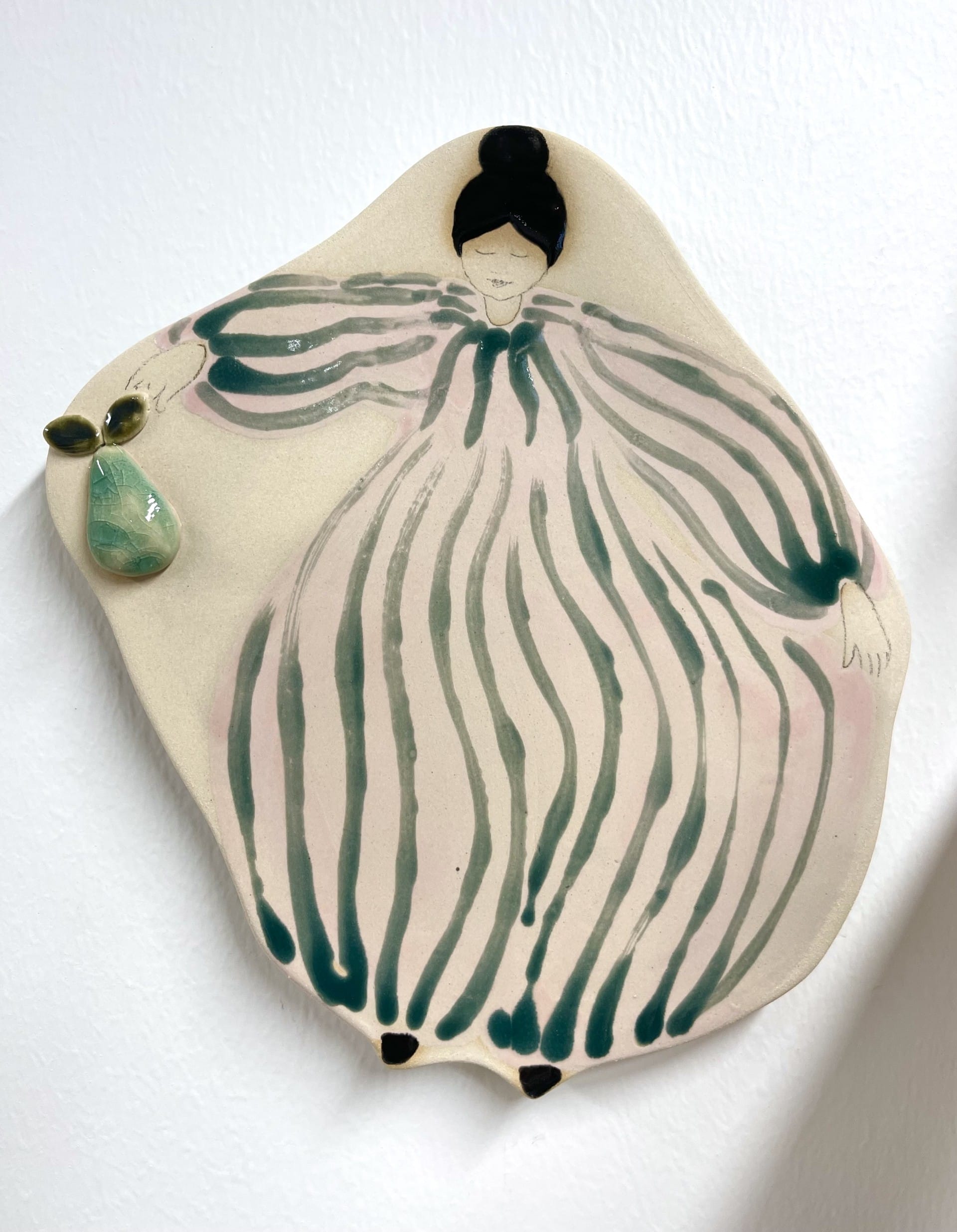 Keraaminen koristelautanen naisen ja päärynän kuvalla.