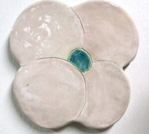 Keraaminen nelilehtinen kukka, keskellä sinistä korostusta.