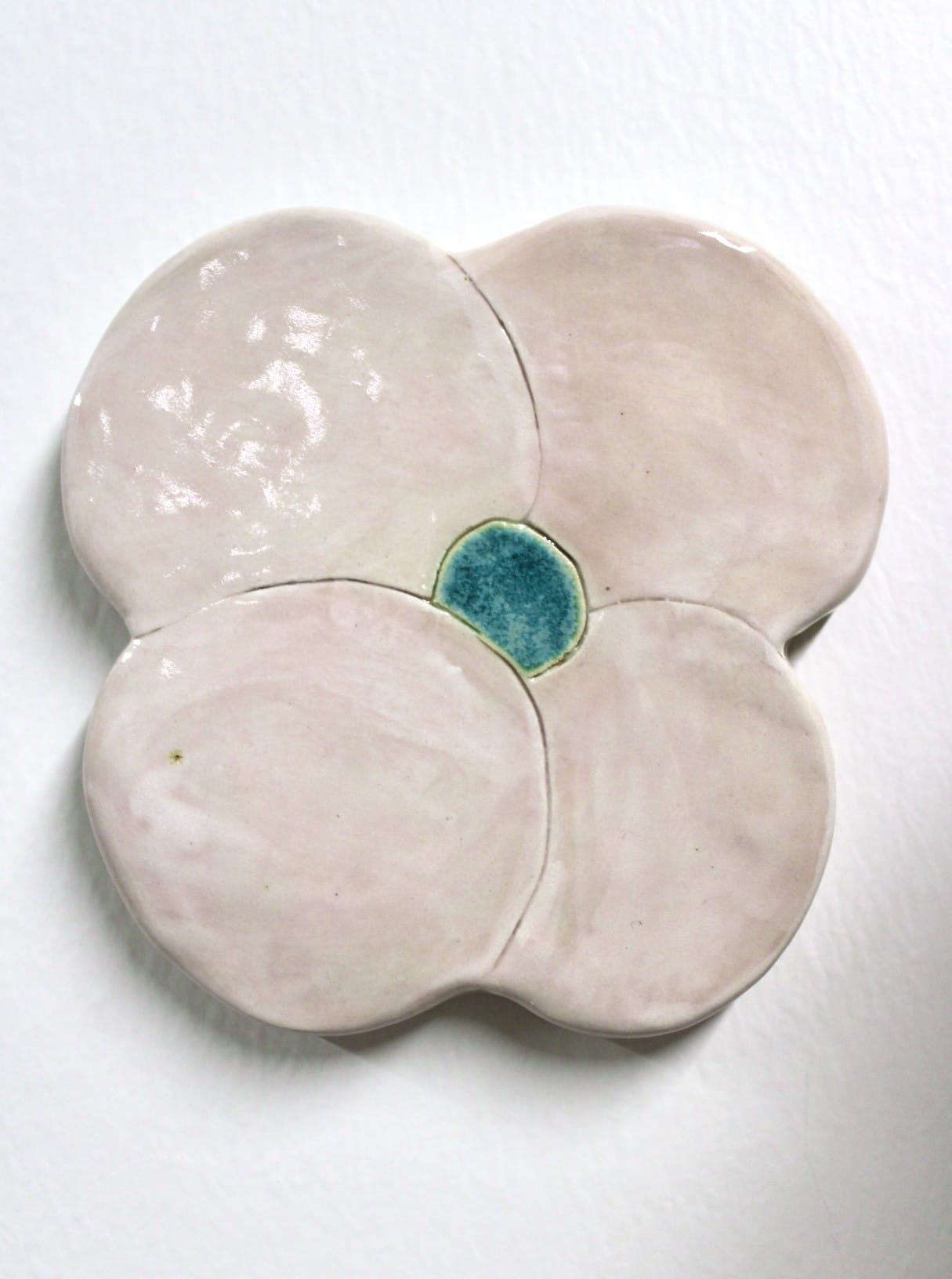 Keraaminen nelilehtinen kukka, keskellä sinistä korostusta.