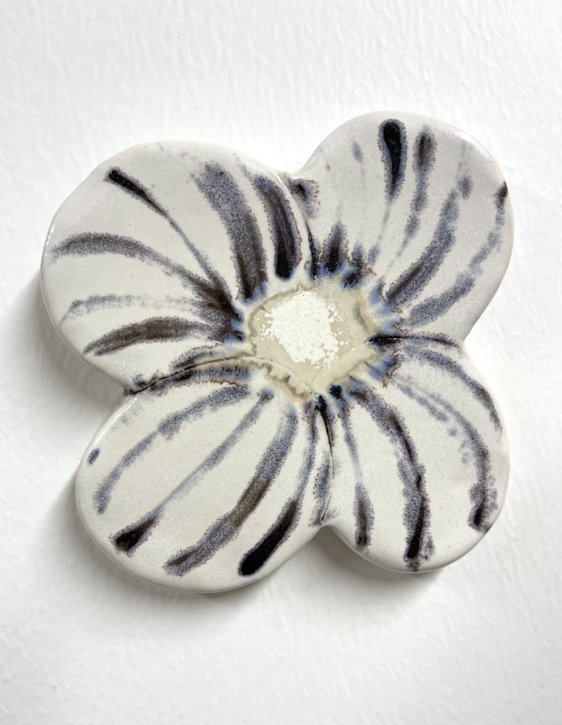 Valkoinen keramiikkakukka mustilla raidoilla