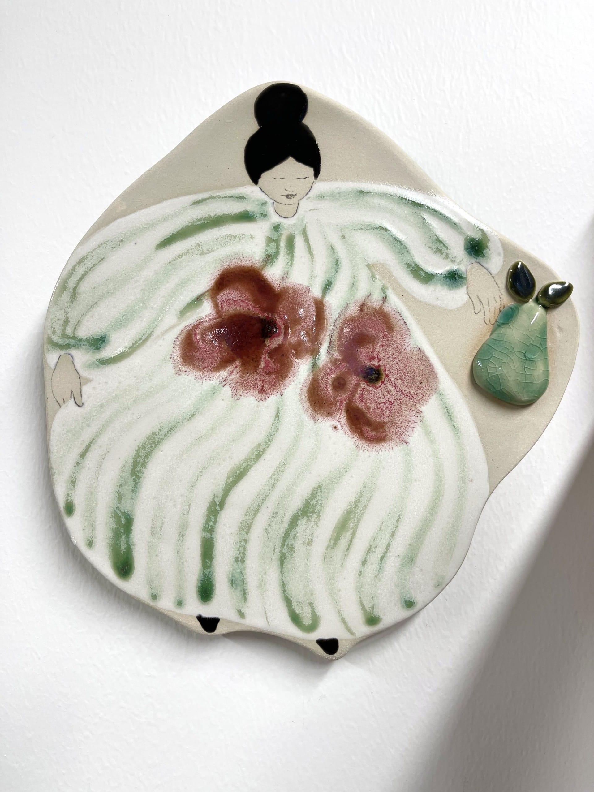 Keraaminen koriste hahmolla ja päärynällä.