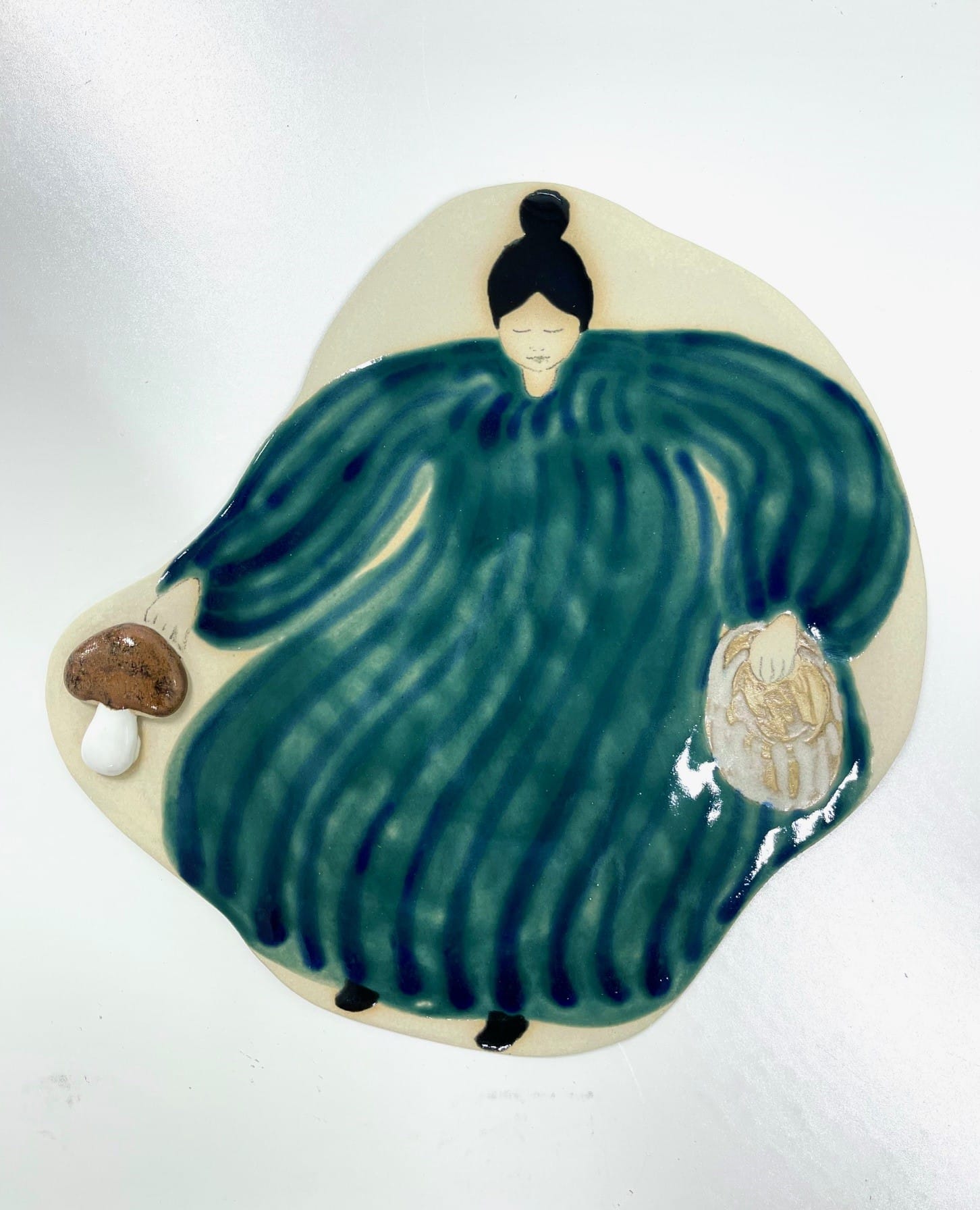 Keramiikkalautanen, sininen hahmo sienellä ja leivällä.