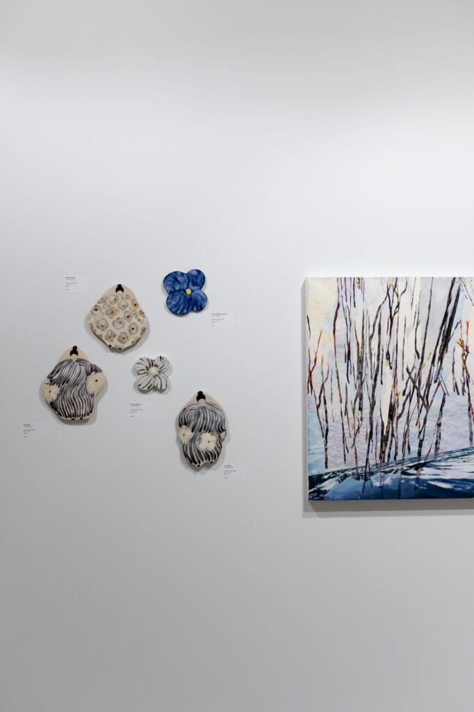 Taidenäyttelyn seinä, keramiikkaa ja maalaus.