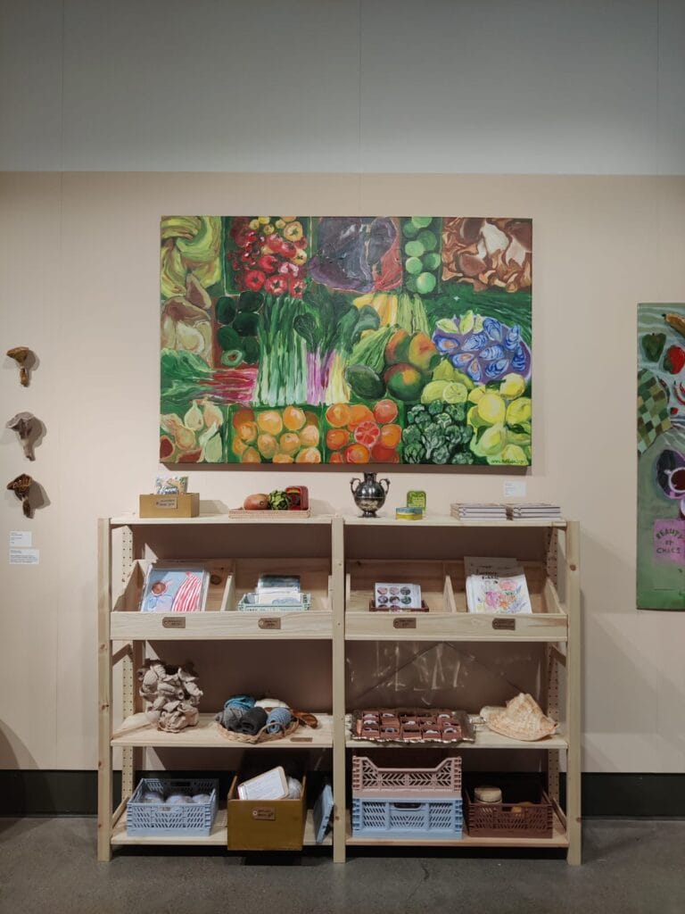 Värikäs hedelmä- ja vihannesmaalaus puuhyllyn yläpuolella.