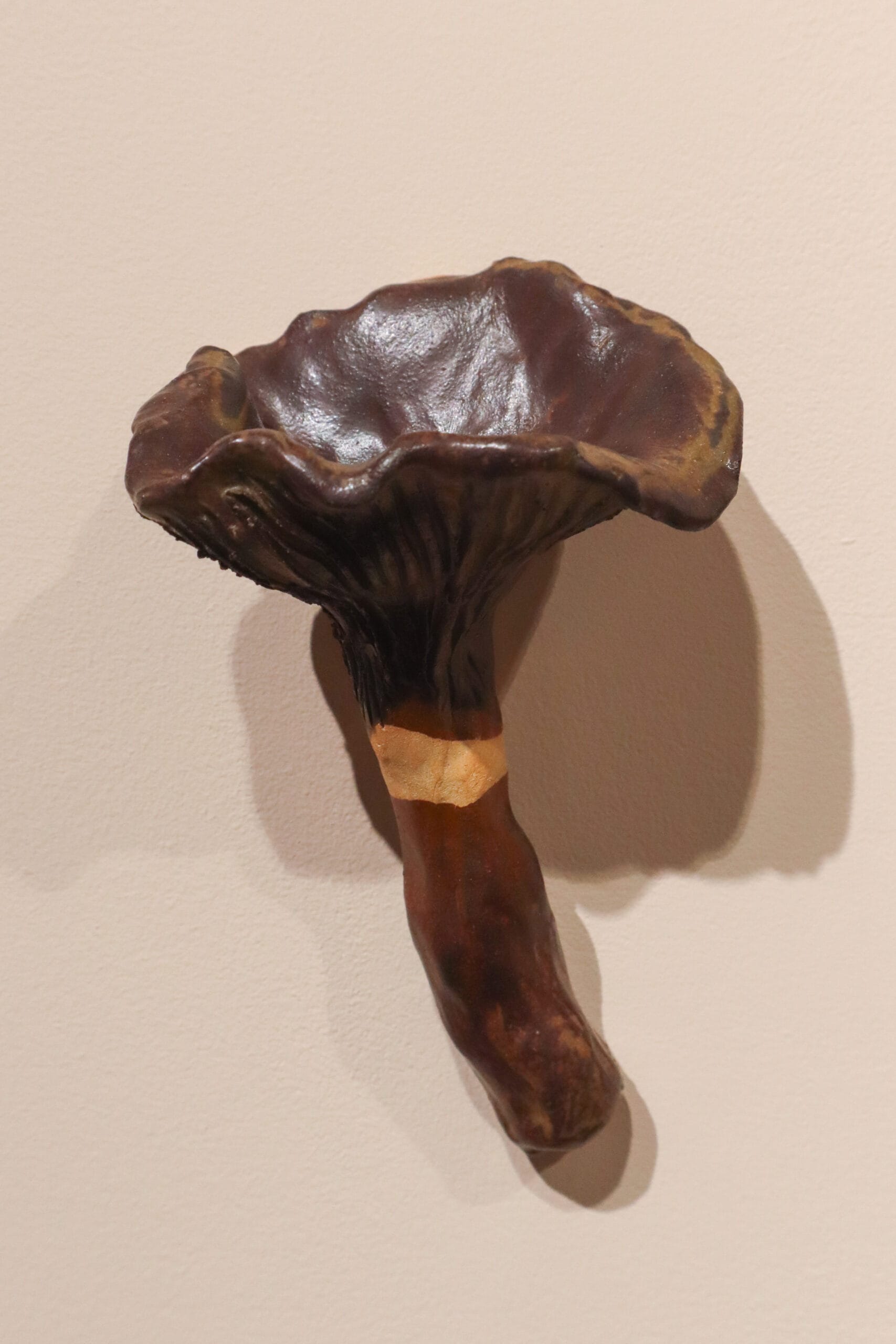 Keraaminen mustatorvisieni vaalealla taustalla.