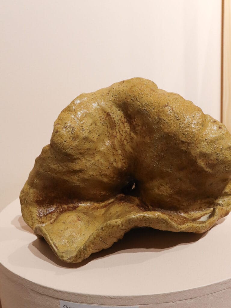 Keltainen, epäsymmetrinen keramiikkaveistos jalustalla.