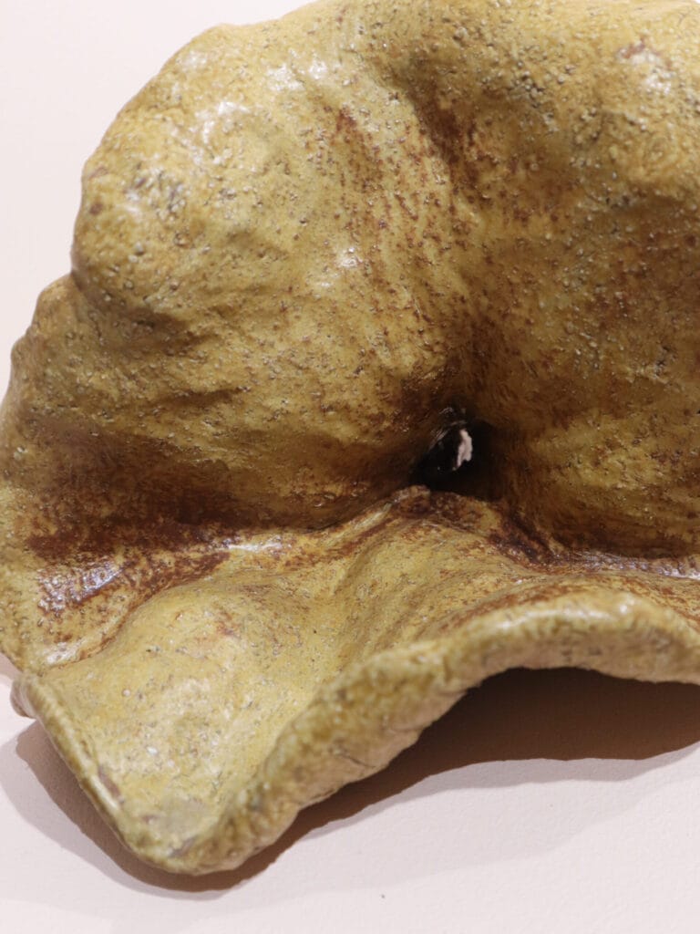 Keltainen, karhea saviveistos lähikuvassa