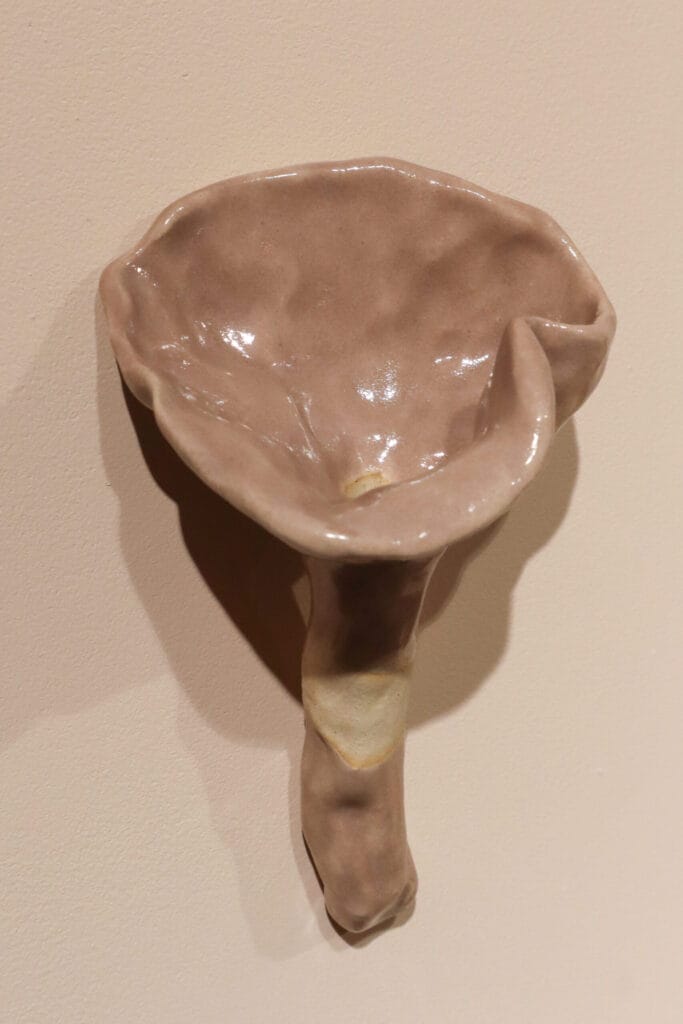 Vaaleanpunainen, käsintehty keraaminen kukka seinällä.