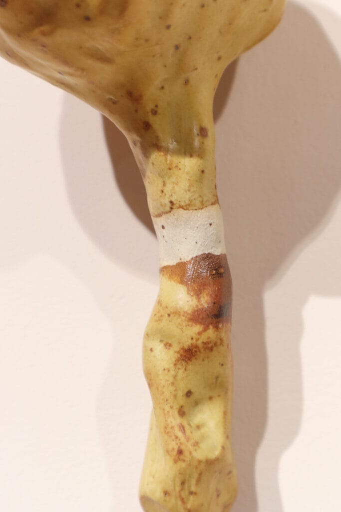 Käsityönä tehty keraaminen jalkaesine seinällä.