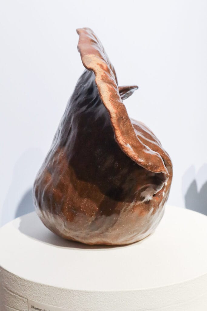 Abstrakti ruskea veistos valkoisella alustalla.