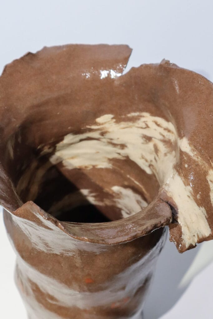 Käsintehty ruskea keramiikkamaljakko valkoisilla yksityiskohdilla.