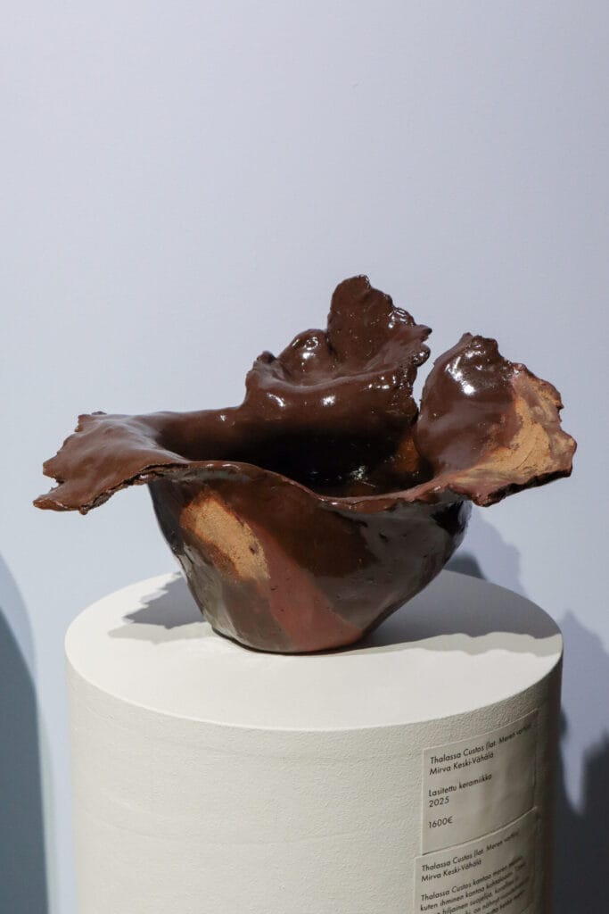 Lasitettu ruskea keraaminen veistos alustalla näyttelyssä.