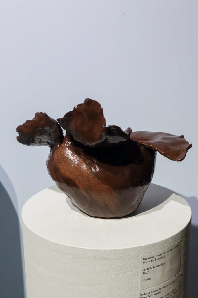 Ruskea keramiikkaveistos jalustalla, moderni muotoilu.