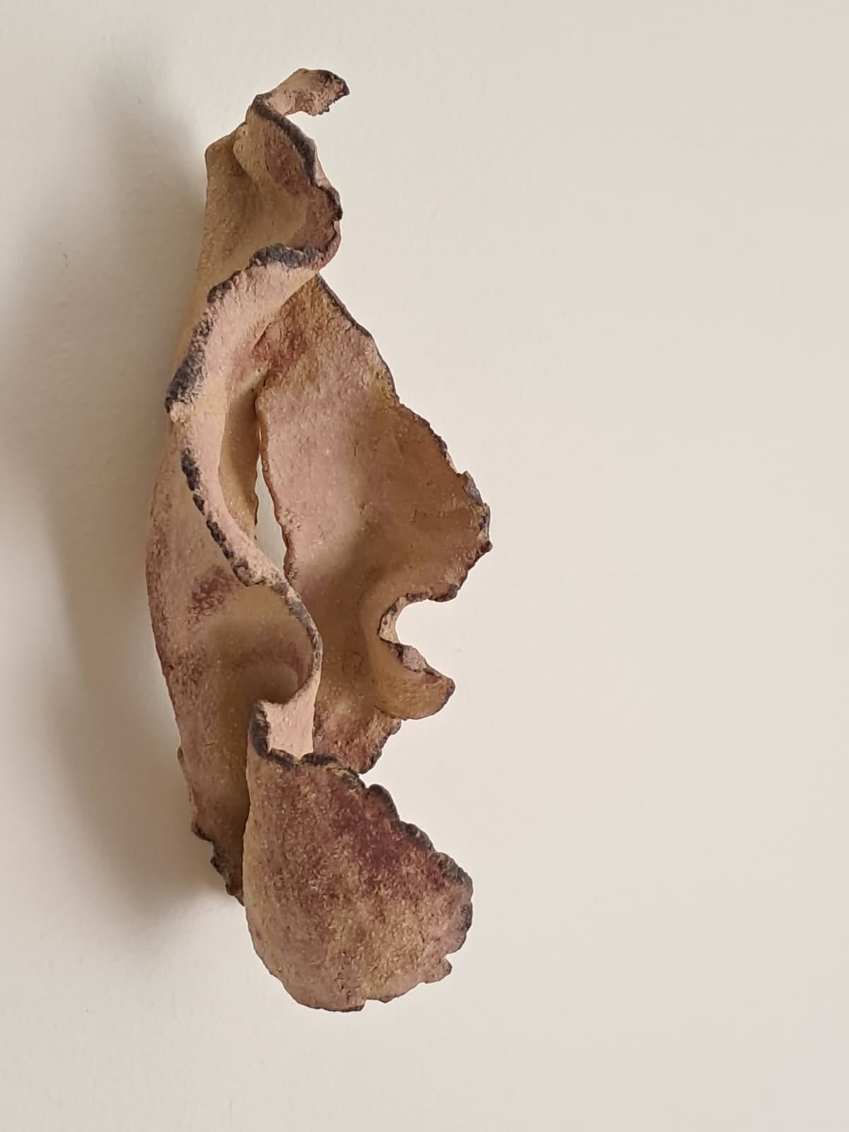 Abstrakti kellertävä puuveistos seinällä