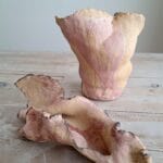 Kaksi epäsäännöllistä ruskeaa keramiikka-astiaa pöydällä.