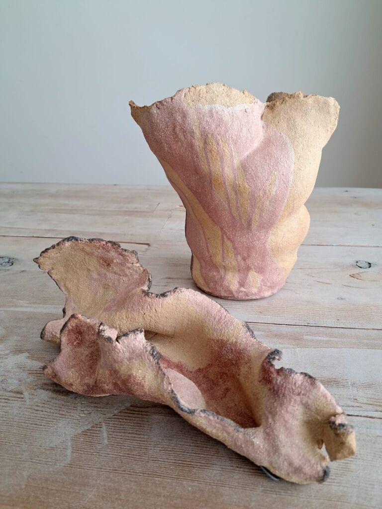 Kaksi epäsäännöllistä ruskeaa keramiikka-astiaa pöydällä.