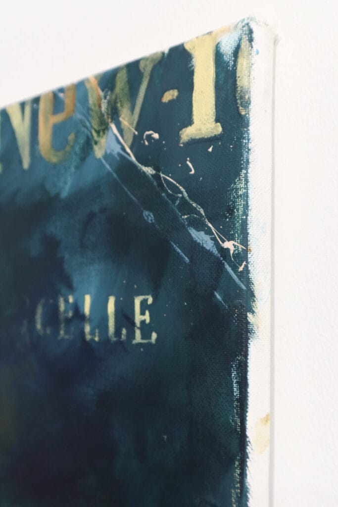 Lähikuva abstraktin maalauksen kulmasta, tekstiä näkyvissä.