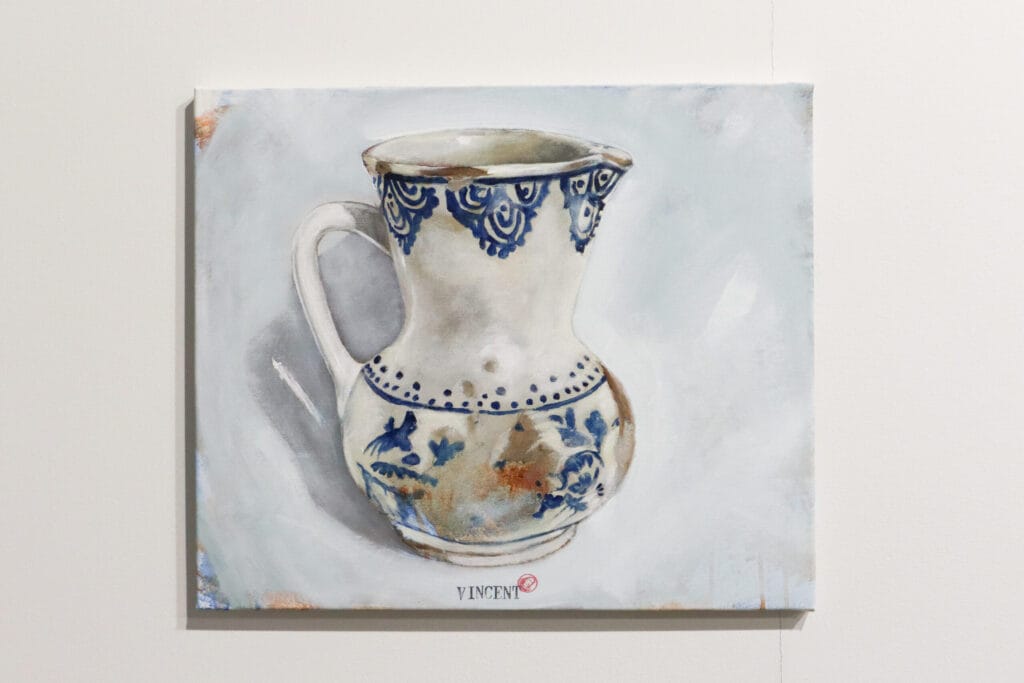 Sinivalkoinen kannu maalauksessa vaalealla taustalla.