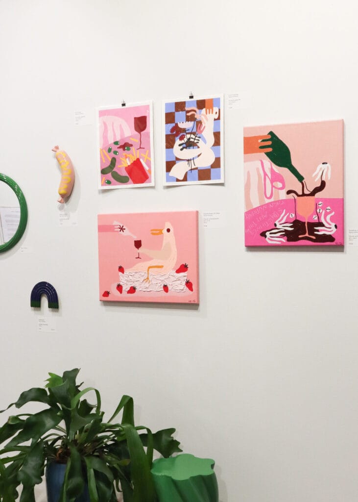 Värikäs galleriaseinä taiteella ja kasvi potissa.