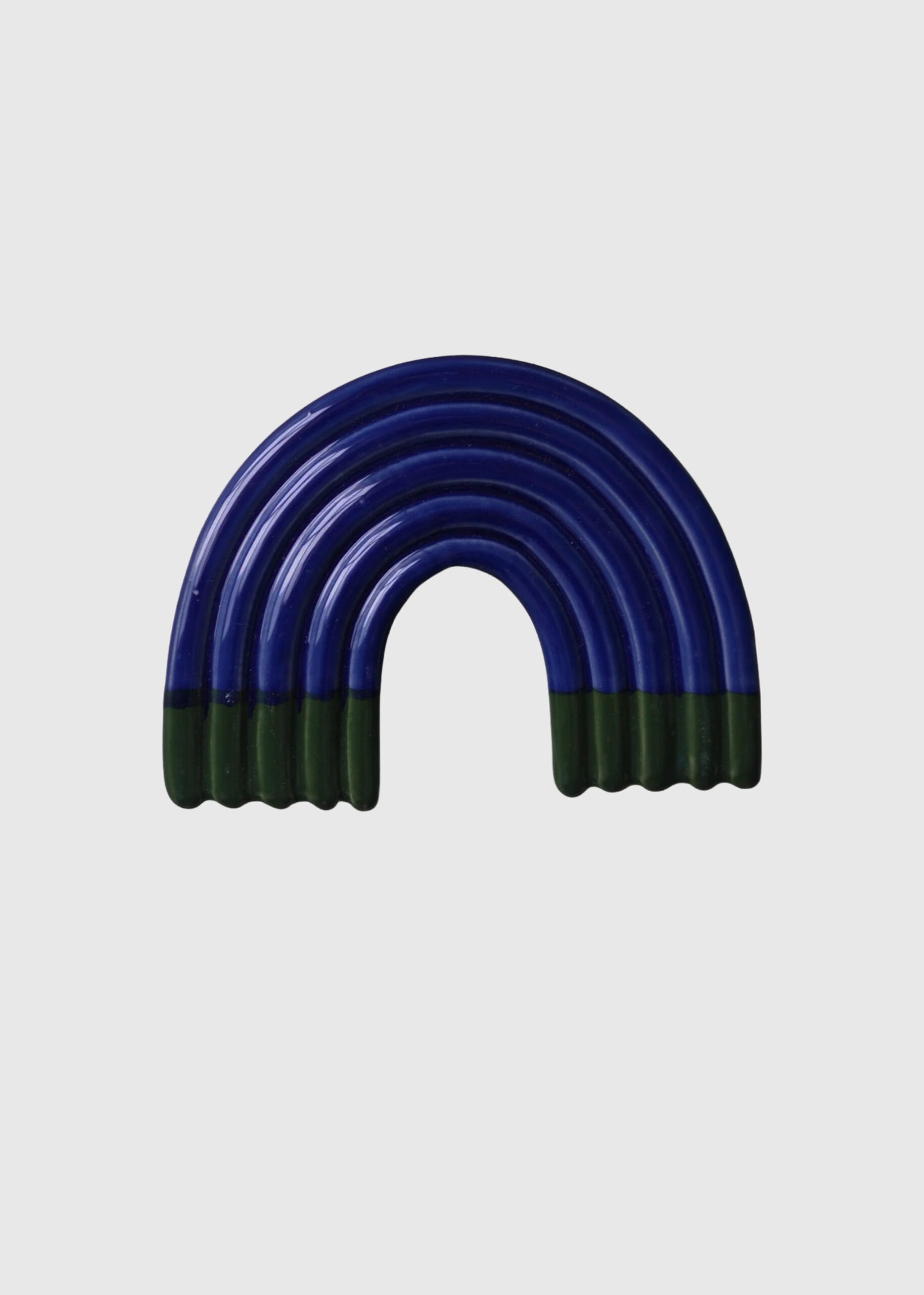 Sininen kaareva keramiikkakoriste vihreillä yksityiskohdilla.