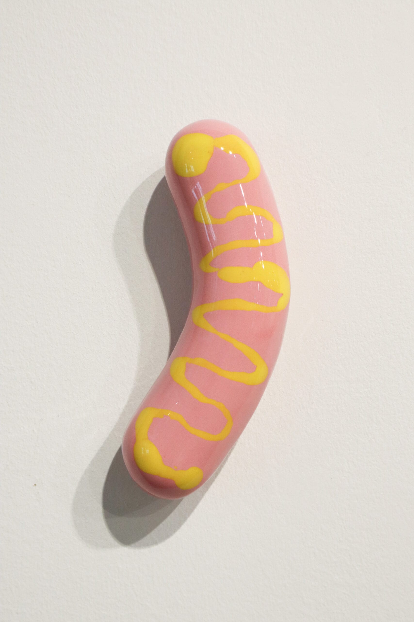 Vaaleanpunainen makkara keltaisella kuviolla, taide-esine.