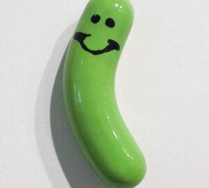 Vihreä hymyilevä suolakurkku valkoisella taustalla