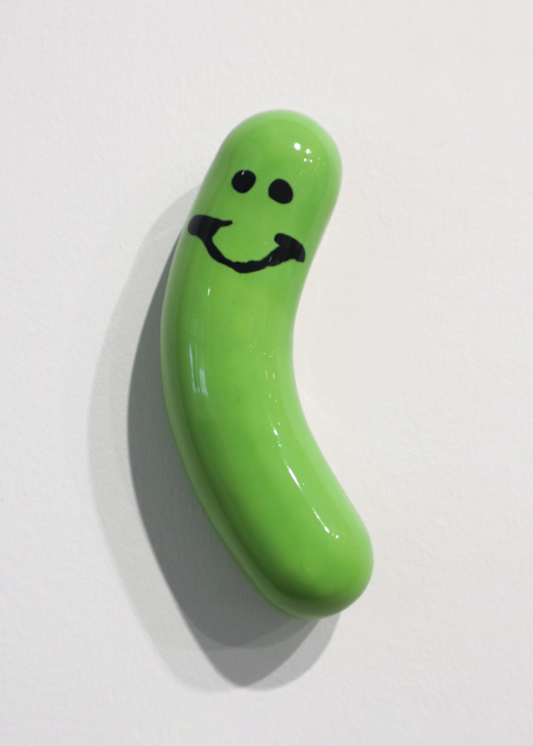 Vihreä hymyilevä suolakurkku valkoisella taustalla