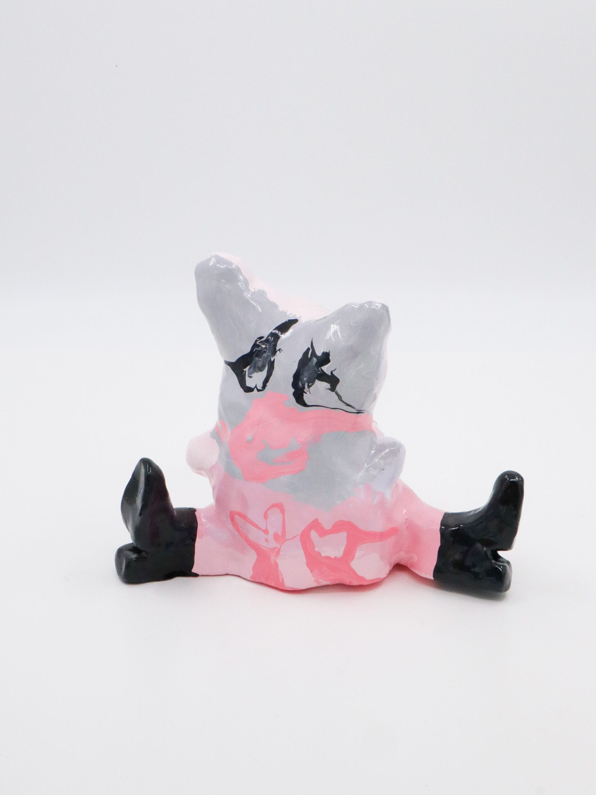 Vaaleanpunainen ja harmaa keraaminen hahmo mustilla saappailla.