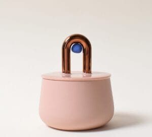 Vaaleanpunainen purkki, metallinen kahva ja sininen koriste.