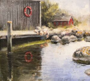 Vanhanaikainen laituri ja punainen talo joen rannalla.