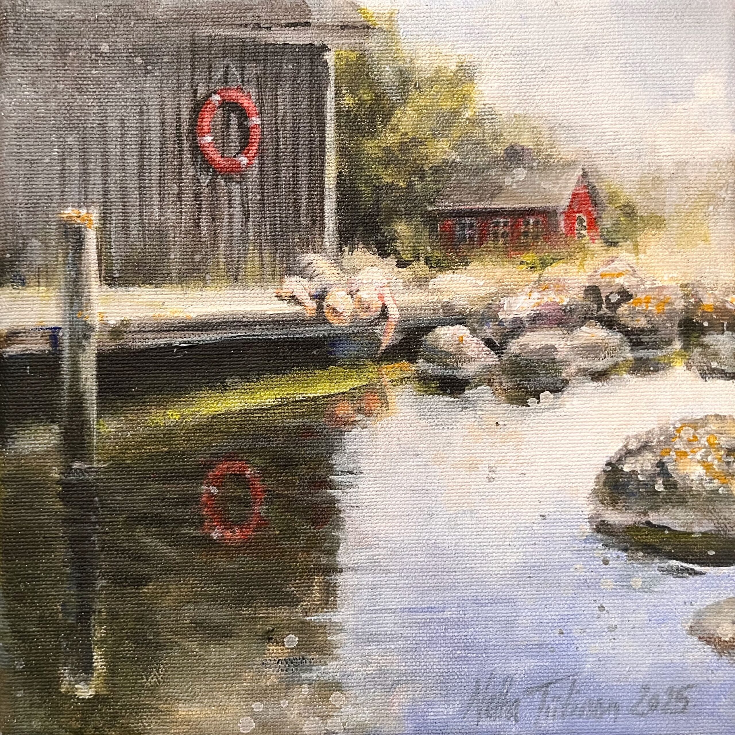 Vanhanaikainen laituri ja punainen talo joen rannalla.